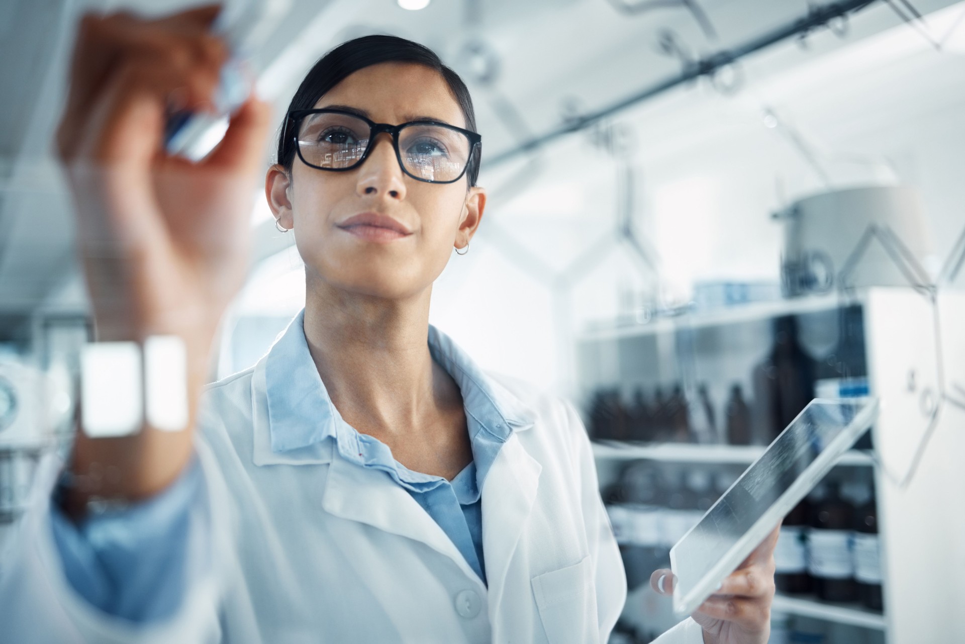 Shot of a young scientist solving equations on a glass screen in a laboratory