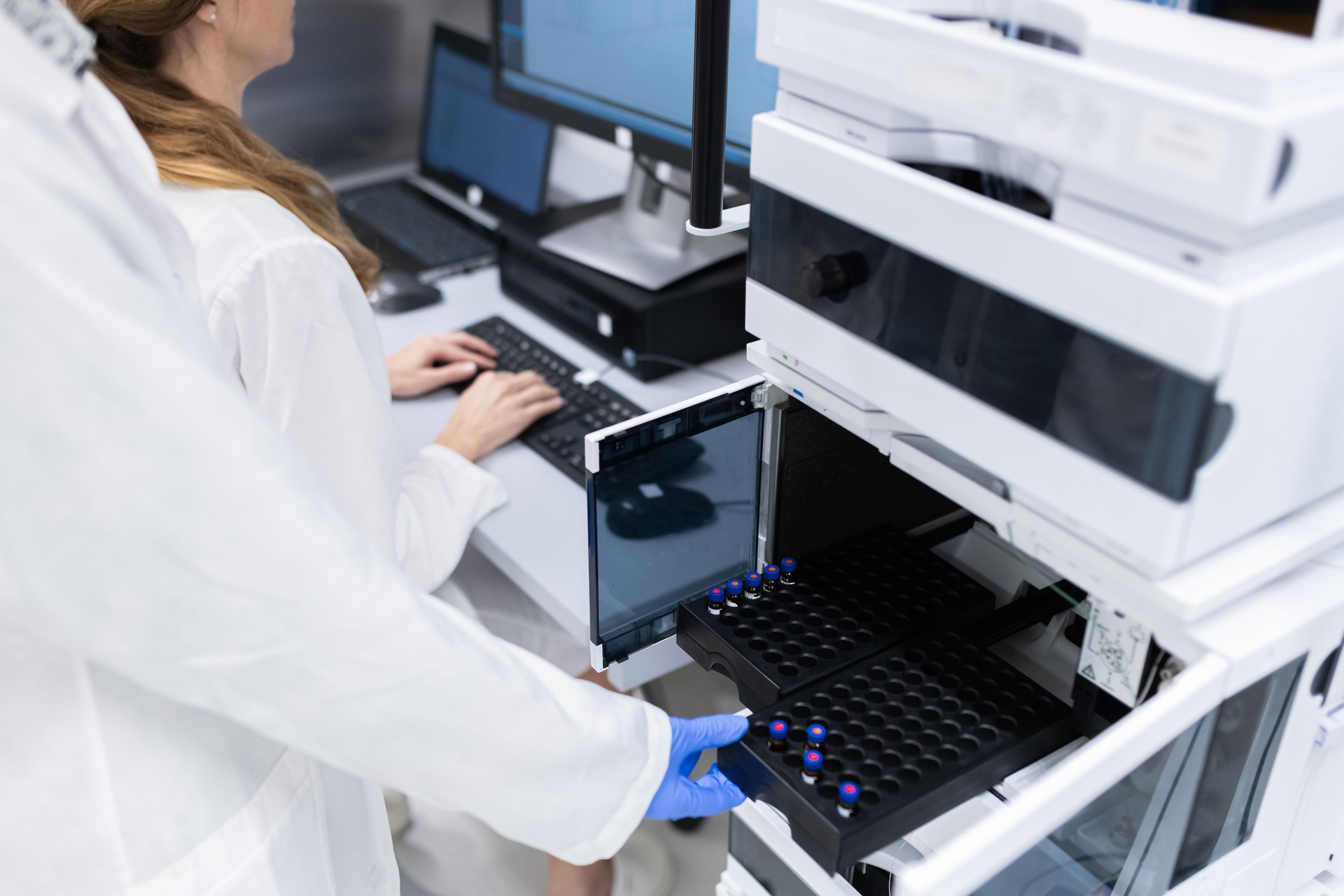 Female pharmacists at work with a device for high-resolution liquid chromatography.